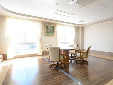 室内の床はフローリングになっており、中央にはテーブルと手すり付きの椅子が置かれている。広い窓からは光があふれている。