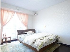 居室にはガラス引き戸があり、ベッド、椅子、ナースコールが設置されている。壁と天井は白色基調になっている。