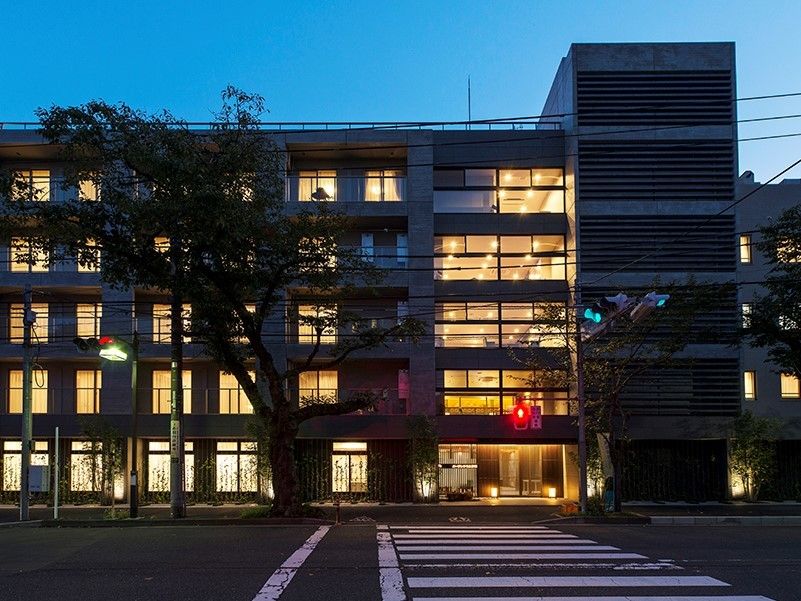 夜間はライトアップされ、正面には大きな街路樹が植えられている5階建ての施設