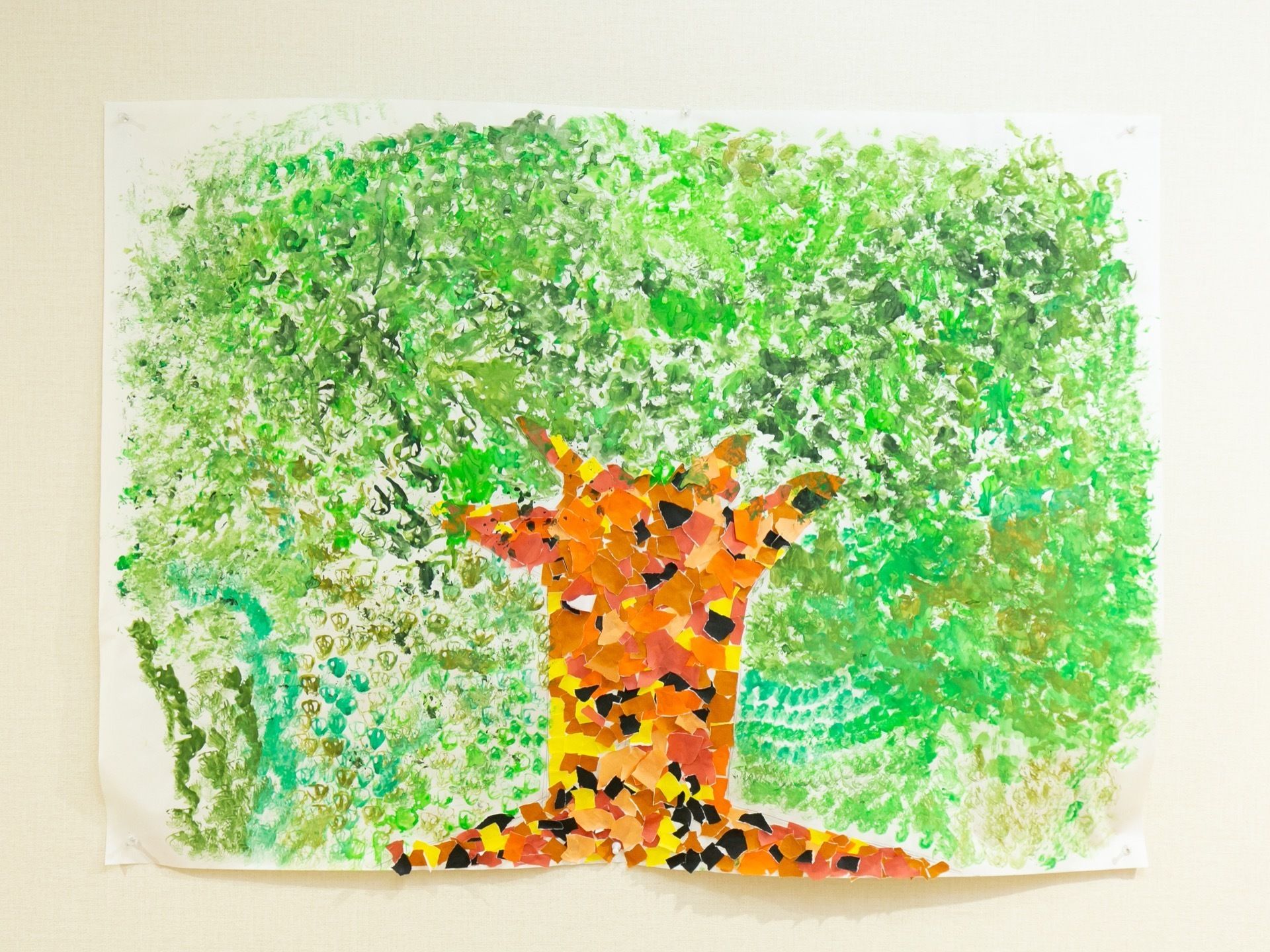 壁に大きな木の貼り絵が飾られている。カラフルな色の紙を切って作られており、細かな工作などを施設で行っている。