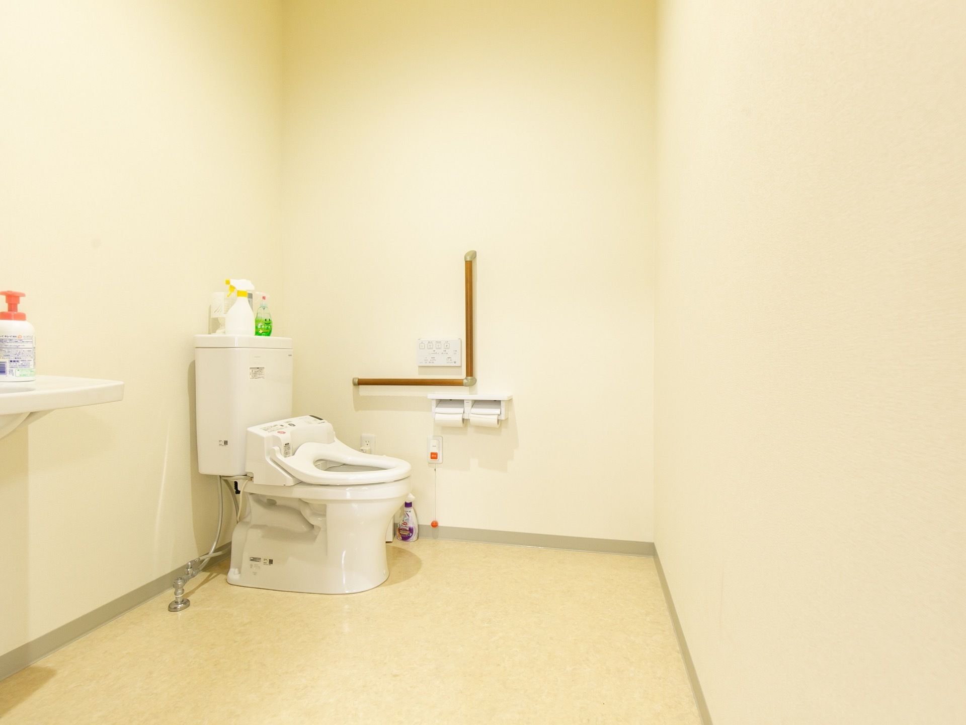 広いスペースに、温水洗浄便座を採用したトイレが設置されている。壁にはL字型の手すりや呼び出しボタンがある。