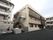 ３階建ての建物を左手前から眺めた様子。建物の周りには木が植えられている。