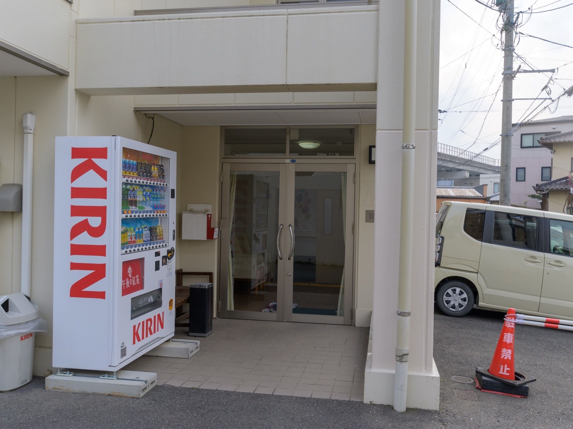 玄関は奥まった所にある。玄関には郵便受けやスタンド式の灰皿がある。大手飲料メーカーの自動販売機が設置されている。