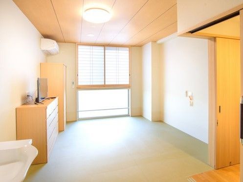 大きな障子の窓があり、エアコンや洗面台、ナースコールのついたバリアフリーの居室