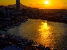 オレンジ色の夕日に染まる、船が並んで停泊している港の風景