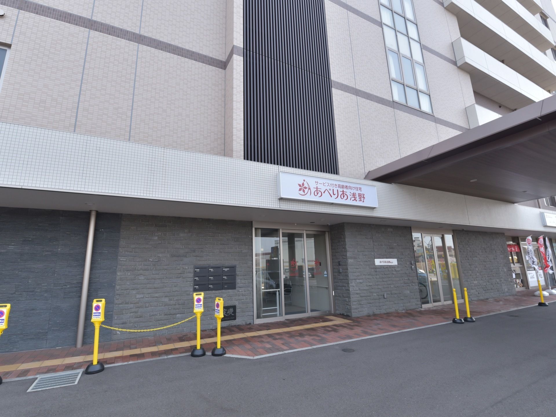施設はグレーのマンションのような外観で、入口はガラス製の自動ドアとなっている。入口の上には、施設名の看板がある。