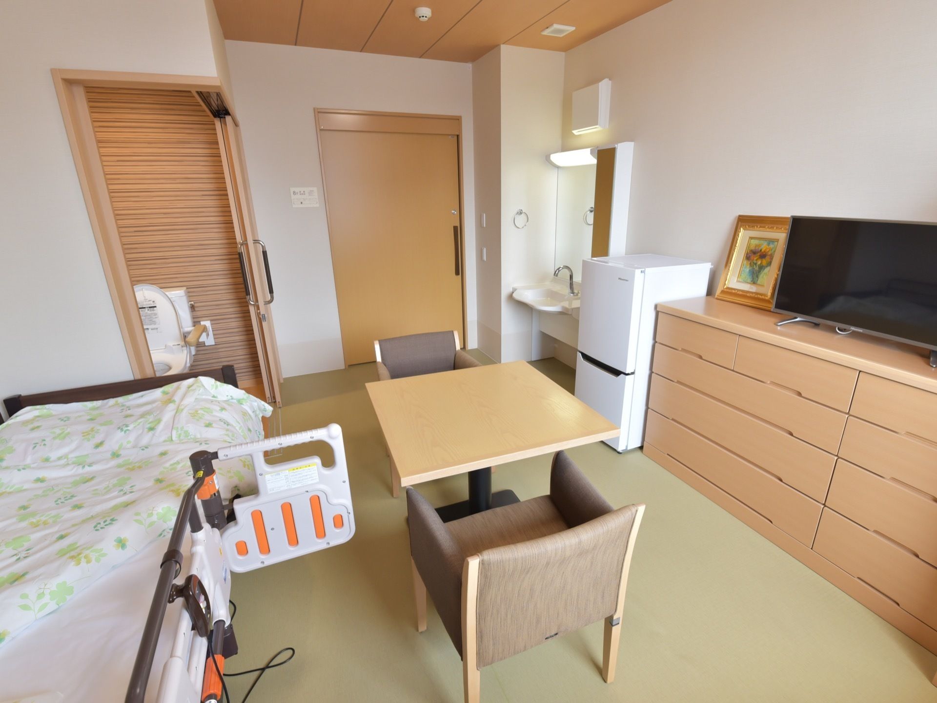 居室のドアはスライドタイプで、部屋の中にトイレや洗面台も設置されている。壁際にはベッド、テーブルや椅子、タンスなどもある。