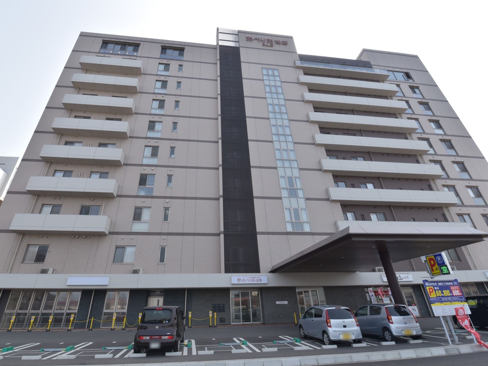 グレーの高い建物で、ホテルのような外観になっている。１階部分と一番上の階の外壁に、施設の名前が表示されている。