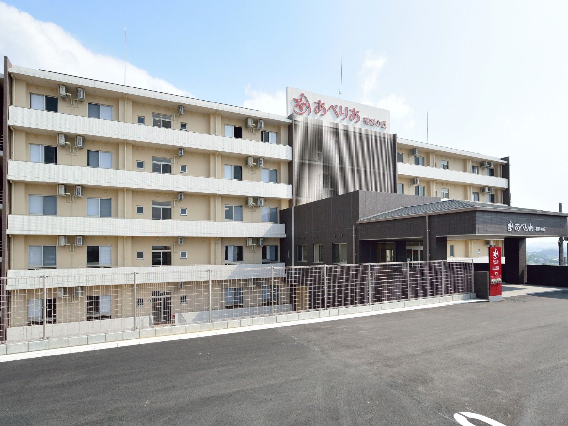 クリーム色の壁に居室の窓が並ぶ外観。傾斜地に建っているため、玄関がある階より下にも居室があるつくりになっている。
