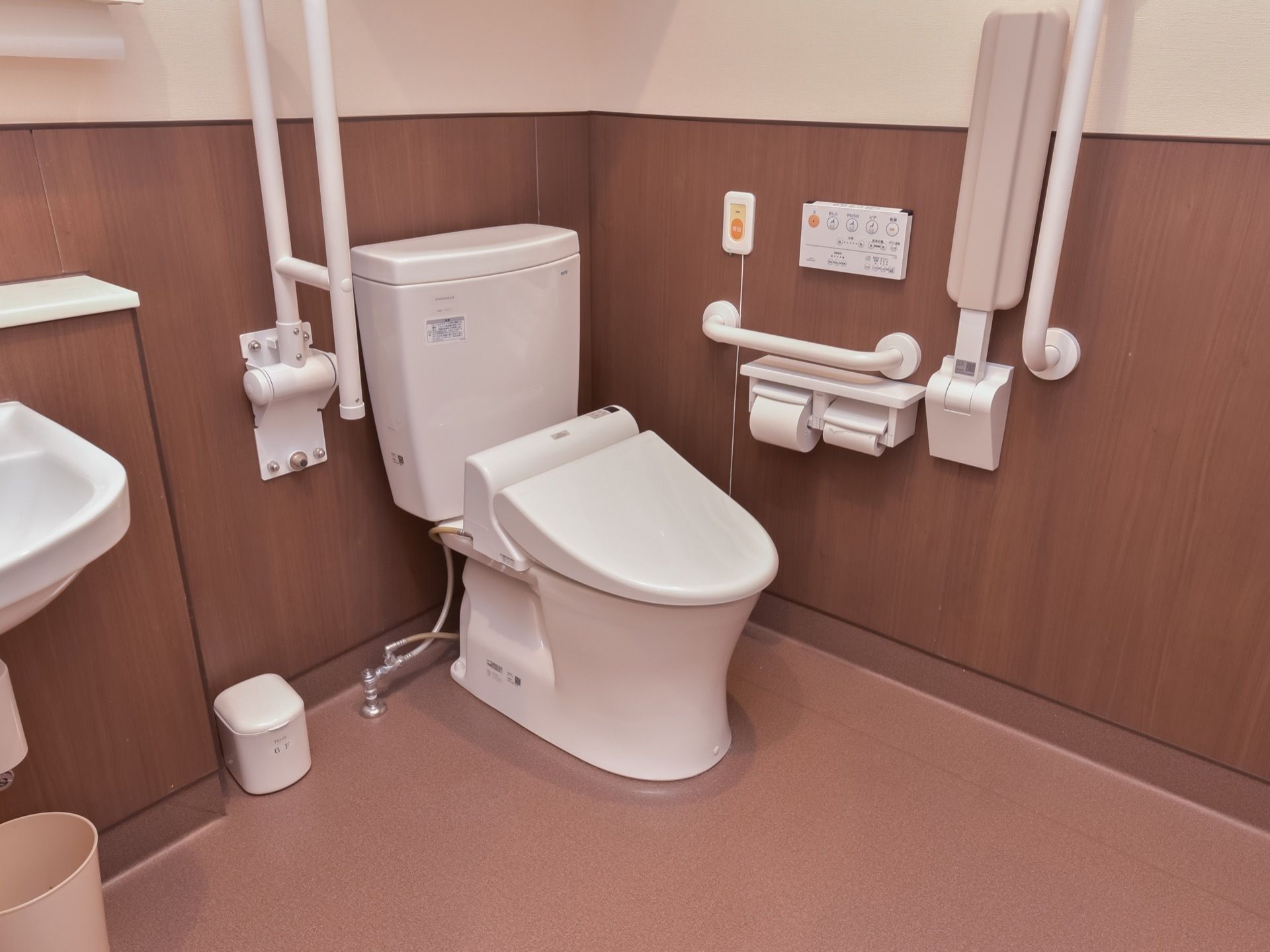 トイレは温水洗浄便座を用意している。壁面には各所に手すりを配置している。折り畳み式のひじ掛けと、緊急用ブザーを設置している。