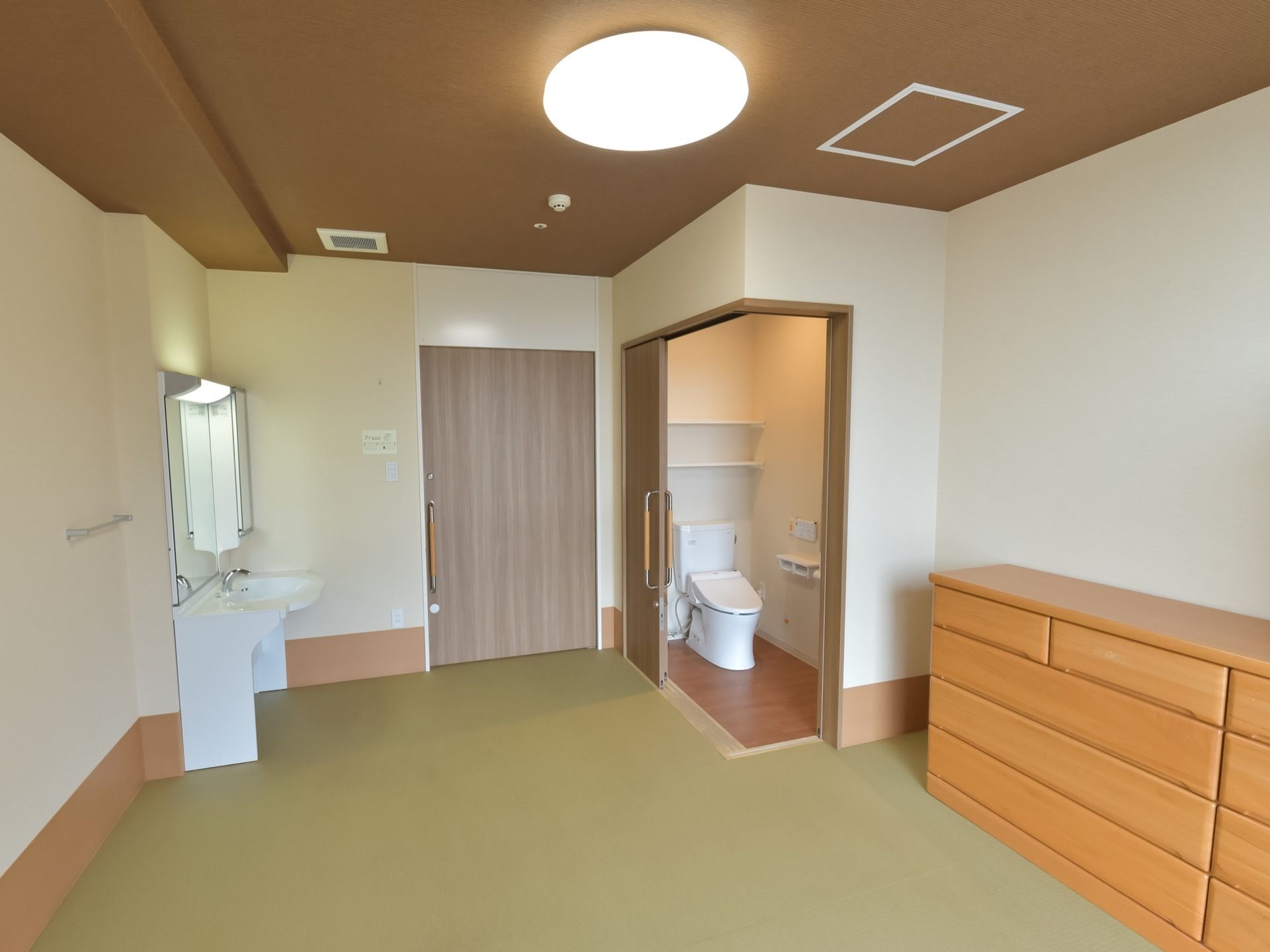 居室の一例。入ってすぐ左手にはトイレがあり、右手には洗面台がある。収納は壁側にチェストが置かれている。