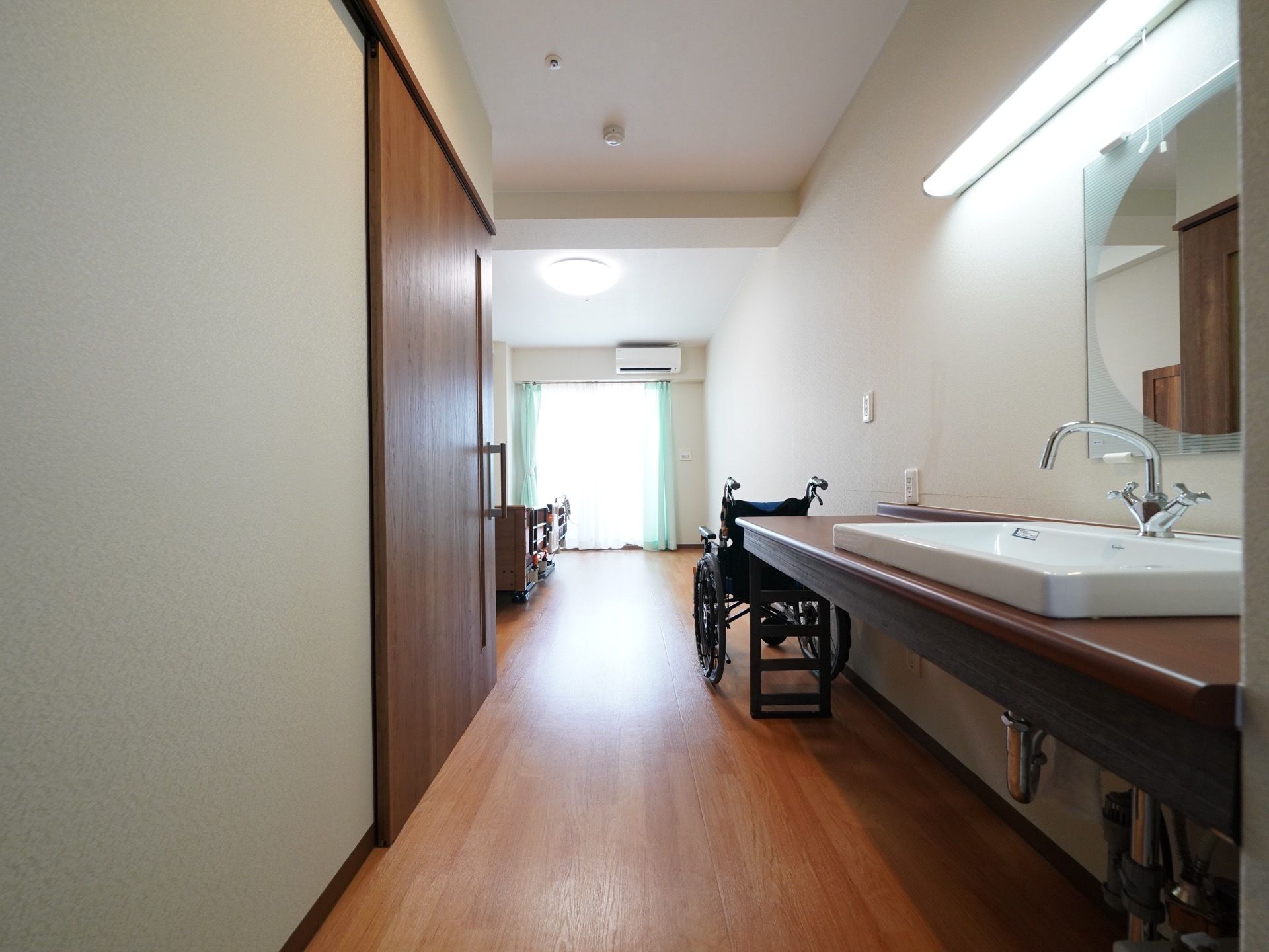 ダークブラウンと白を基調とした居室である。洗面所やトイレ、キャビネットが備わっている。洗面所は足元がないタイプである。