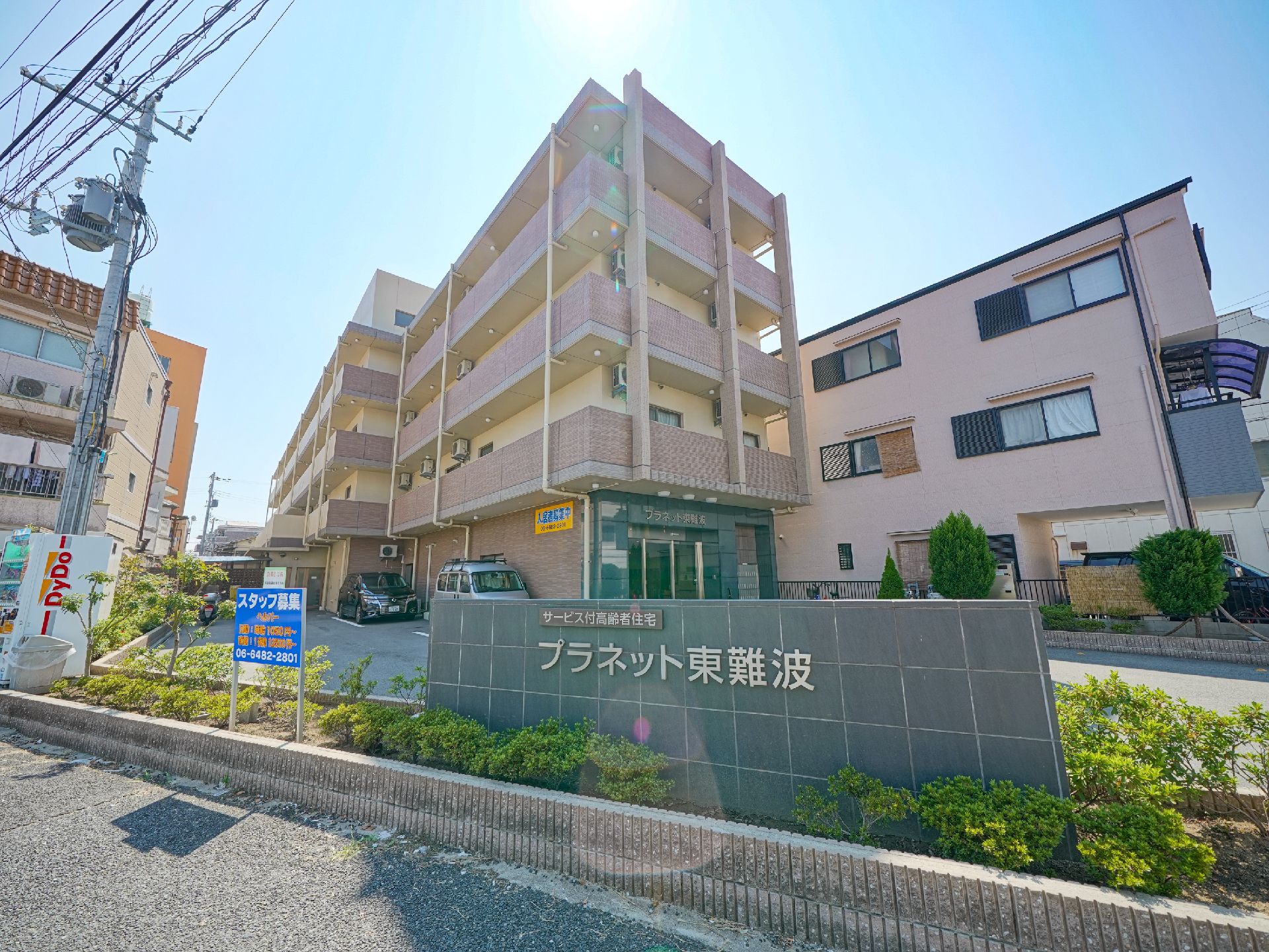 道路沿いの植え込みの中に設置された、石造りの施設看板