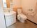 広々とした清潔感のある明るいトイレである。最新式の洗面台や非常用呼び出しブザー、手すりが完備されている。