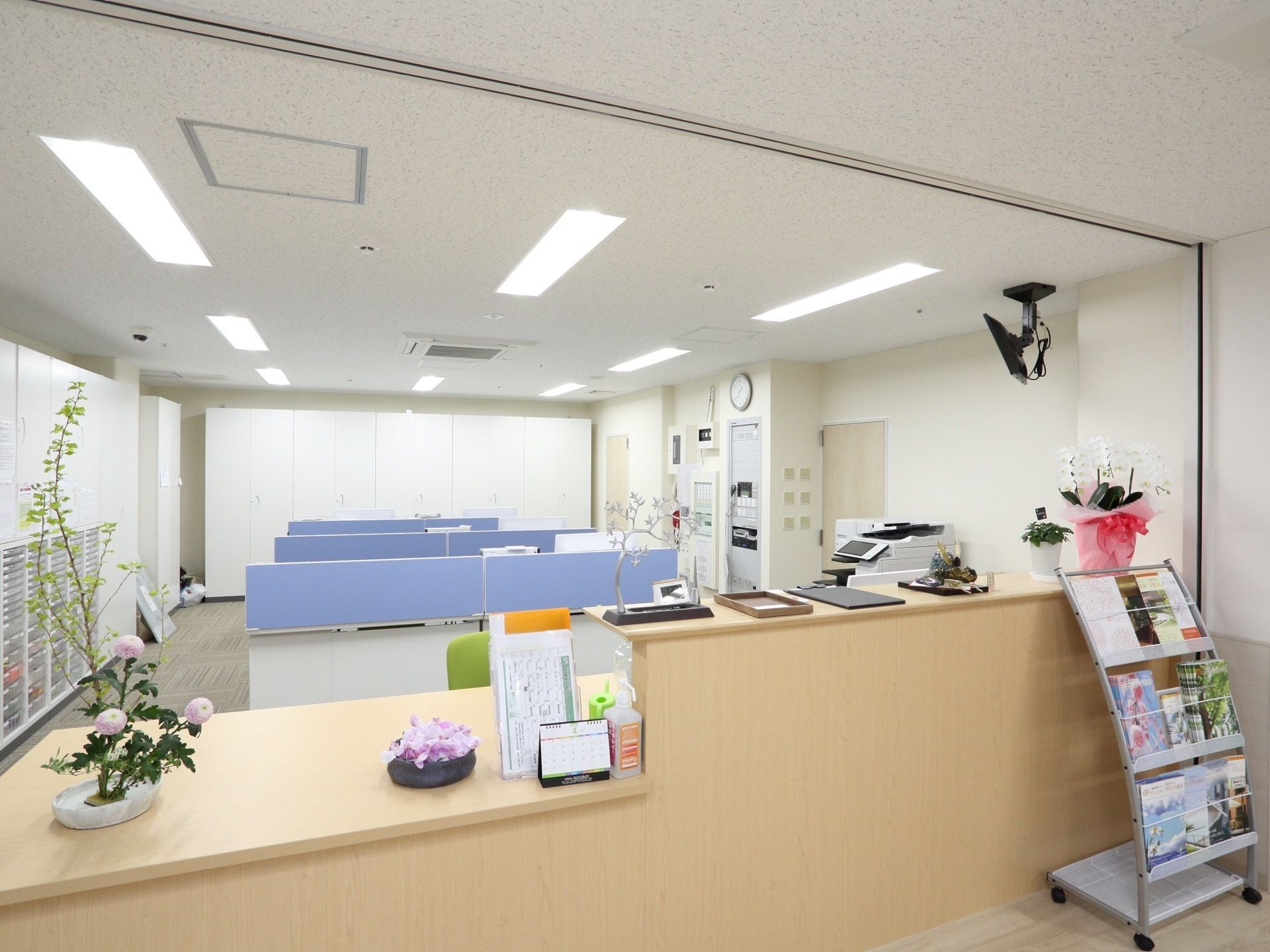 デスクなどが並んでいる空間があり、その前にはカウンターが設置されている。カウンターの上には生け花などが置かれている。