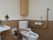 トイレタンクの上部に収納が設置されている。温水洗浄便座が設置されている。木目調を基調としたトイレである。