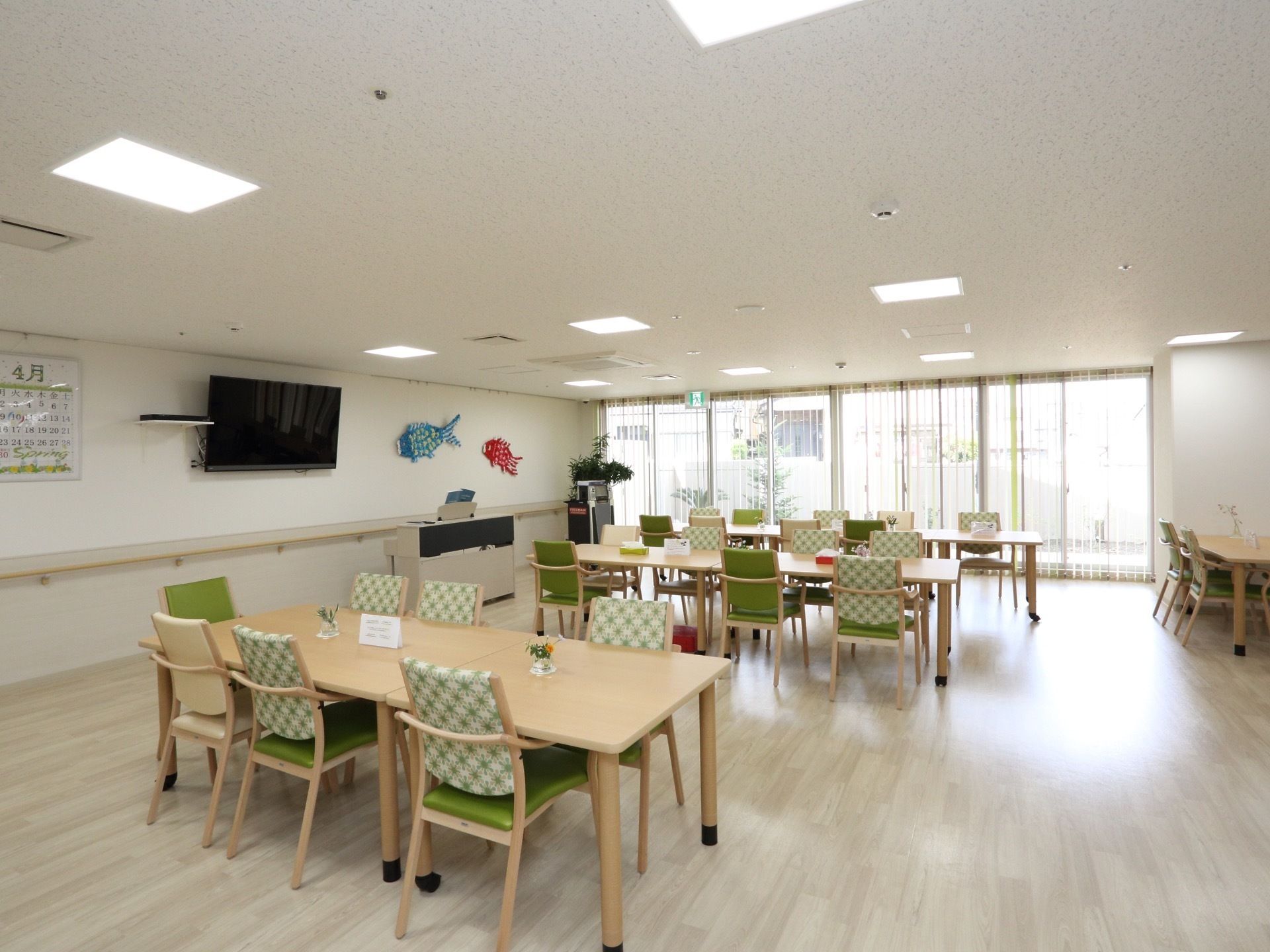 とても広く明るい空間にテーブルや椅子が置かれている。白を基調とした空間に、緑の椅子が際立って見える。