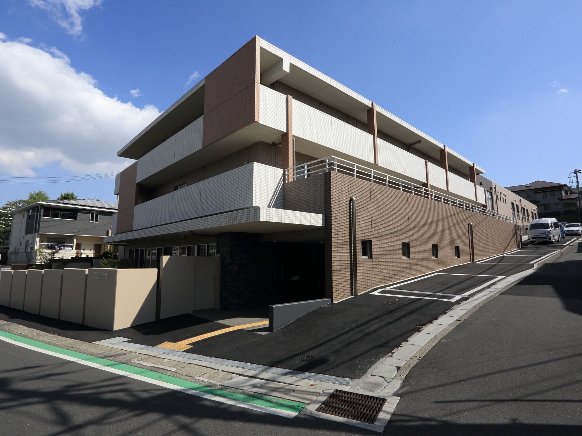 緩い坂道沿いに建つ、塀に囲まれた3階建てのお洒落な施設