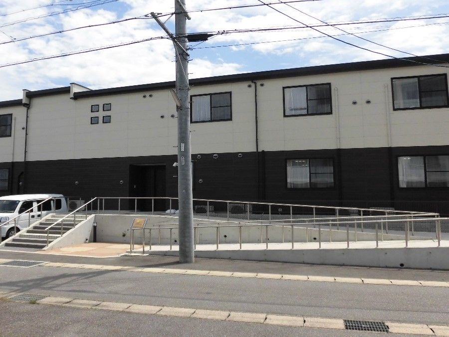 施設は２階建てで横に長い作りの建物である。壁の色には白と黒が用いられており、落ち着いた様相をしている。手前には駐車用のスペースがある。