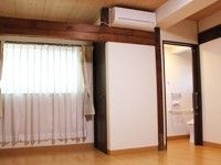 トイレの扉が開いており、洋式便器が一据見えている。大きな梁が通っており、その上にはエアコンが設置されている。