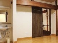 居室の扉の上には大きな梁が通っており、やわらかな空間を演出している。手洗い場が設けられており、鏡が掛けられている。
