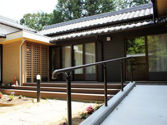 入口まではスロープが設けられているので、歩行器や車椅子をご利用の方でも通行しやすくなっている。花壇には花が植えられている。