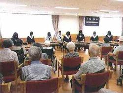 高齢者の方々に見守られながら楽器を演奏する学生たち