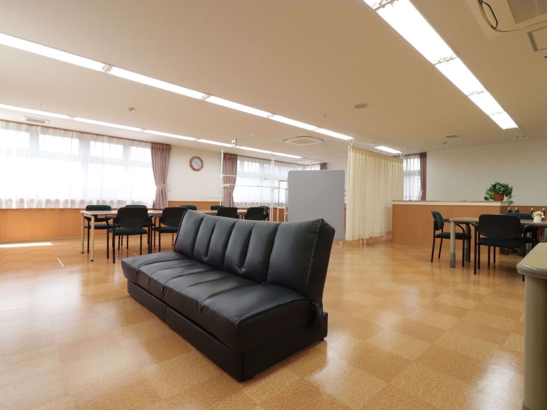 広々とした空間に大きなソファー、椅子とテーブルなどが置かれている。床はバリアフリーでチェック柄になっている。