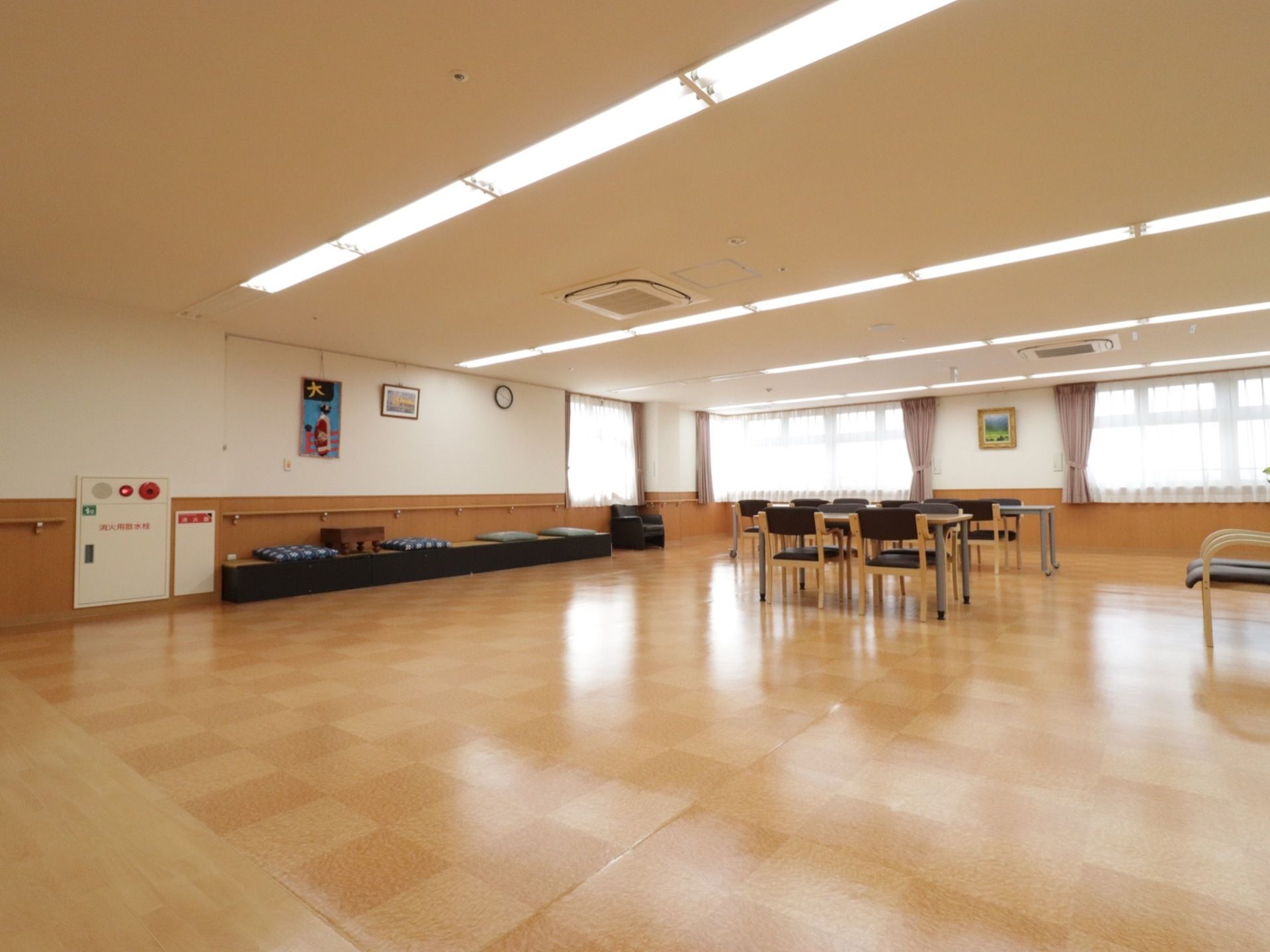 市松模様の床はバリアフリーになっている。壁側に手すりとベンチが置かれ、囲碁も用意されている。壁には絵が飾られている。