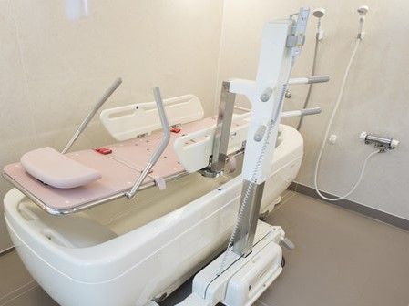 2つのシャワーの前に置かれた、寝た姿勢で入浴できる介護用入浴機器