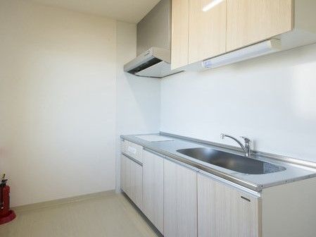 片隅に消火器が置かれた、電気調理器のついたキッチンスペース