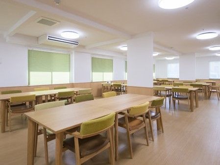 複数並べられたテーブルセットの中に丸柱の立つ、広い共有スペース