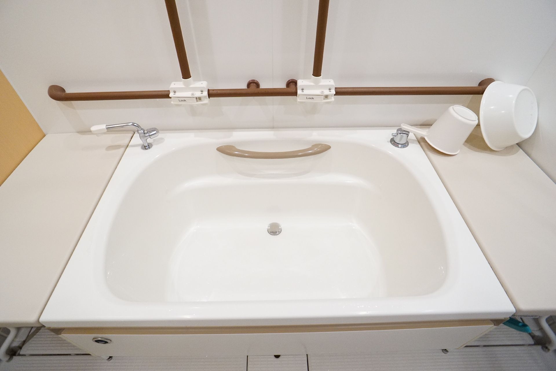 壁に茶色い手すりが付いた浴室