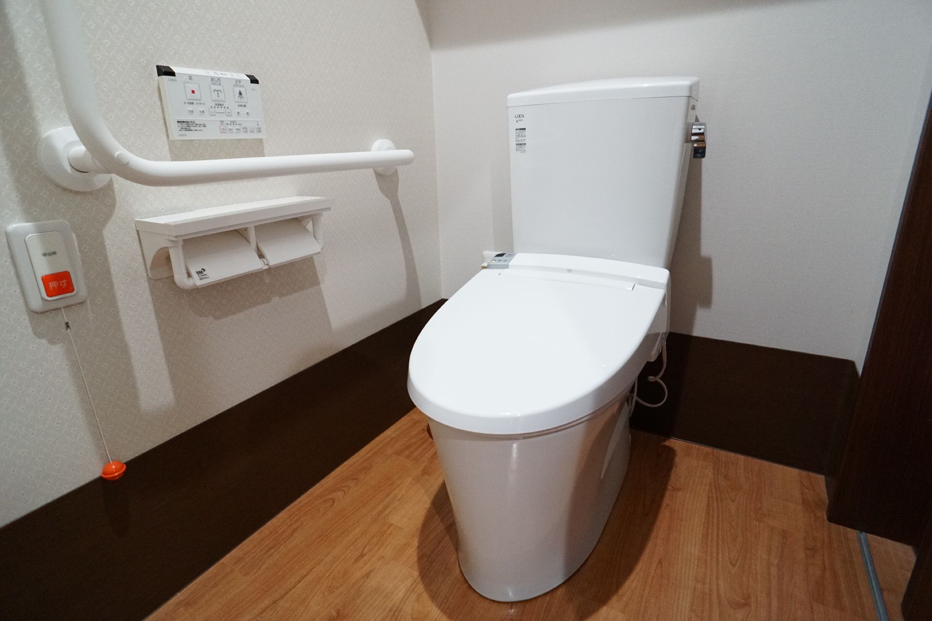 白い壁に白い手すりが付いたトイレ