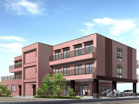 ブラウン系の色合いで統一した外観の建物で、２階より上にはベランダが備わっている。玄関前などには木が植えられている。