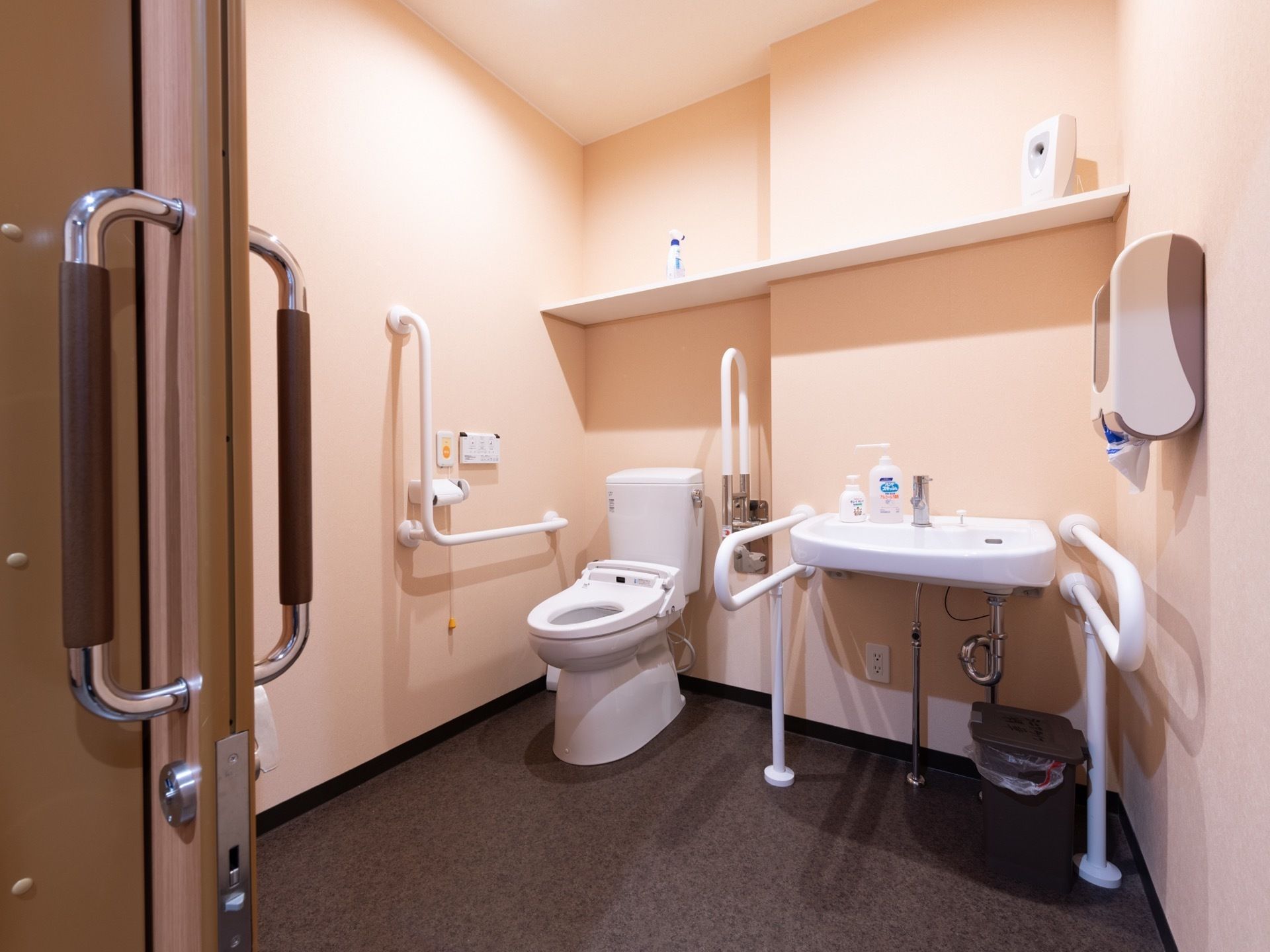 車椅子でも余裕を持って入れる広いトイレがある。便座周りには手すりがついており、隣には洗面設備もある。
