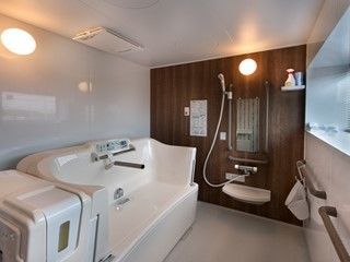 モダンで清潔感のある浴室には転倒防止のための手すりを取り付けている。また介護用の機械浴も設置されている。