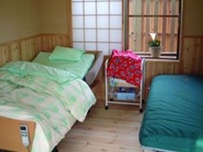 介護ベッドや長椅子が置かれた、障子窓で板張りの部屋