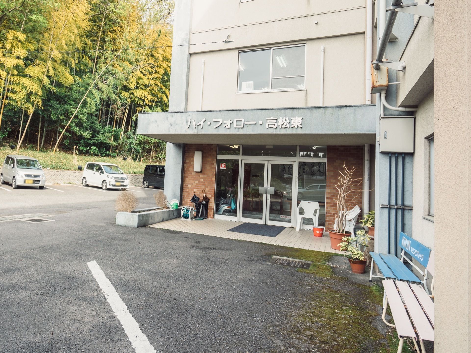 ガラス戸の玄関ドアの傍には、白い椅子を置き、反対側に傘立てを備えている。敷地内には、駐車スペースを設けている。