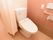 居室内のトイレは、カーテンで仕切られている。温水洗浄便座が設置され、手すりやケアコールも取り付けられている。清潔感のある印象を受ける。