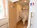 窓の近くに片開きのドアのトイレがある。トイレ前には縦型の手すりが設置されている。その上にトイレマークが貼られている。
