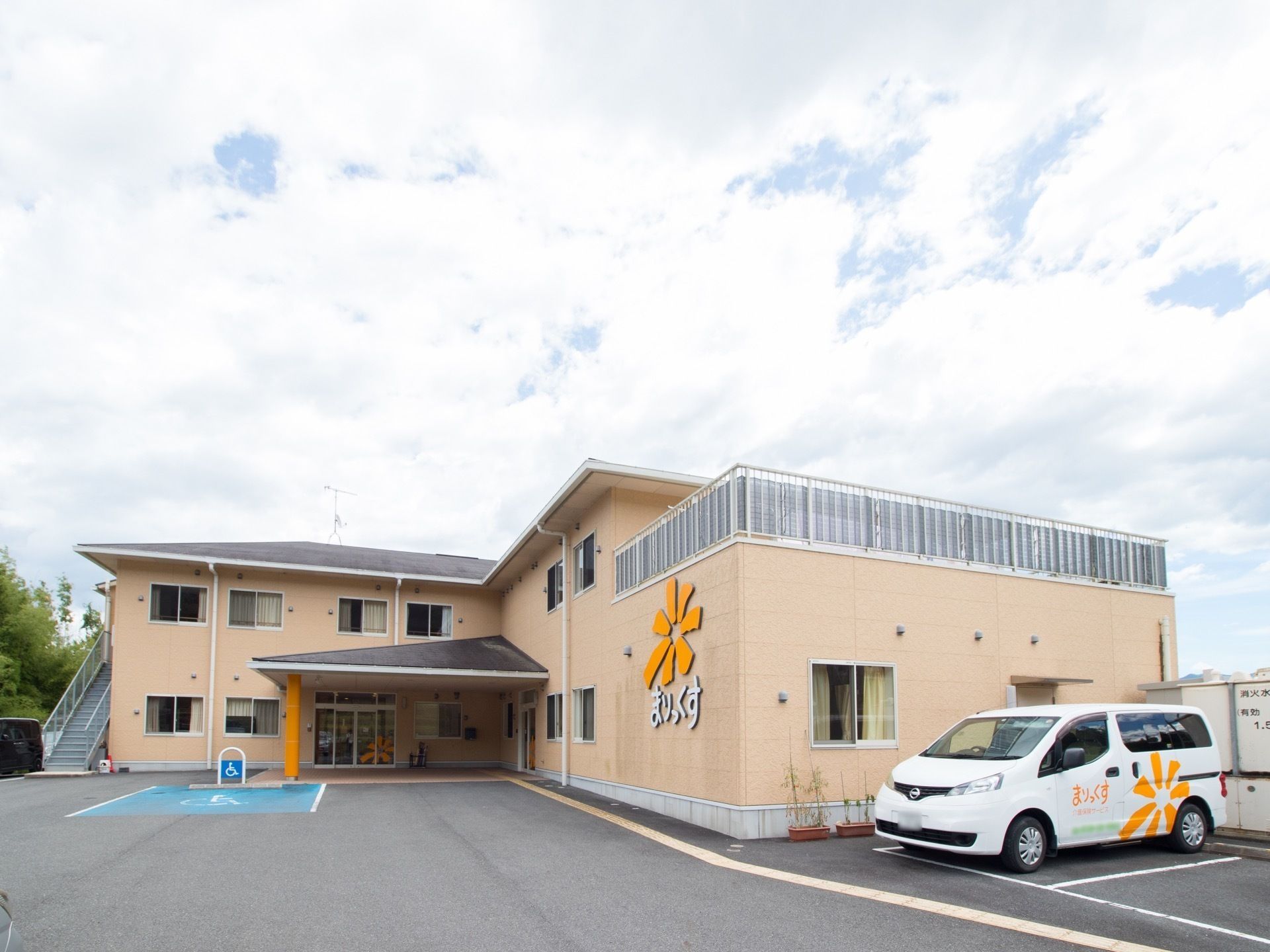 駐車場の奥に建てられた、外階段のある2階建ての建物