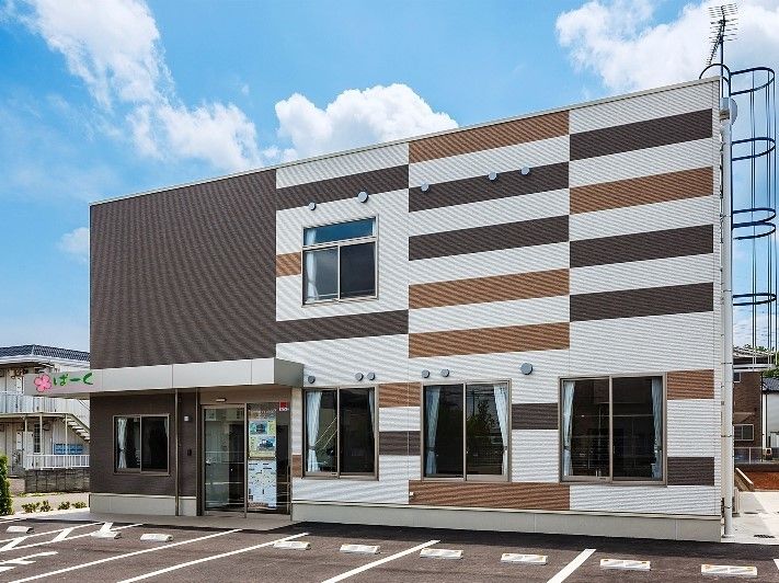 白・黒・茶などを一定間隔で塗った壁が特徴の建物。入り口のすぐ前が駐車スペースで、複数台停められるようになっている。