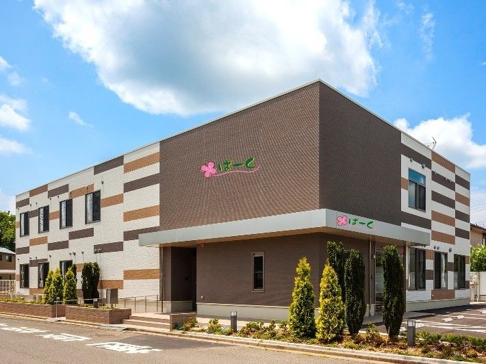 周囲を花壇で囲まれた、寄せ木細工のようなデザインの2階建ての建物