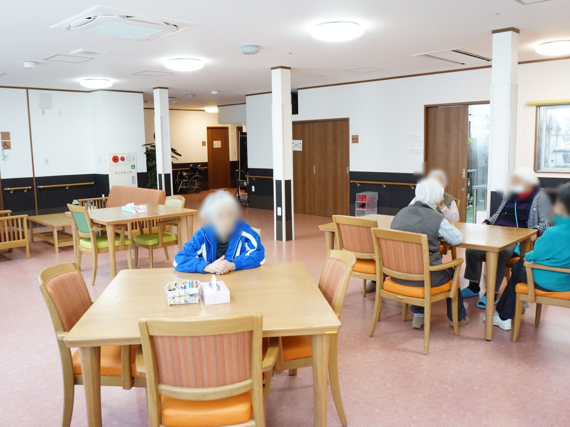 食堂は通路との仕切りがなく、広々としている。壁には手すりが設置されている。入居者様が共有スペースとして利用している。