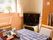 居室に腰高の窓があり、白色の鉢に植えられた植物が置かれている。テーブルに青地のクロスが掛けられている。