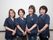 紺色の制服に身を包み、にこやかにほほ笑む４人の女性スタッフである。入居者様のために、親身になり、笑顔で対応している。