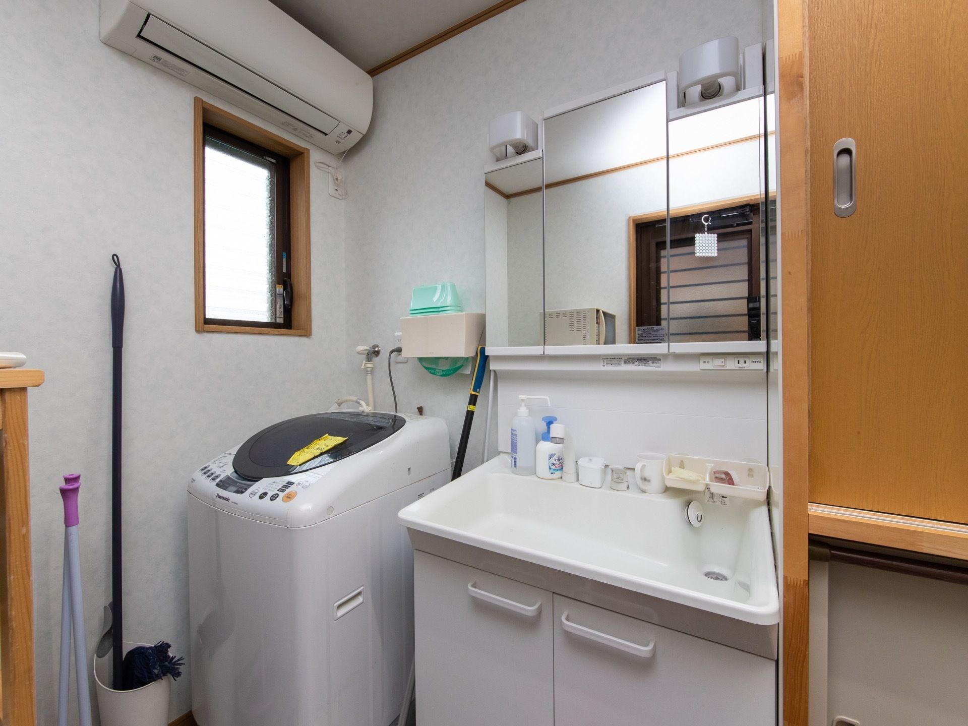 洗面所には、エアコンと洗濯機が設置されている。洗面ボウルと鏡は大きく、足元には扉がついている。また、掃除道具が用意されている。