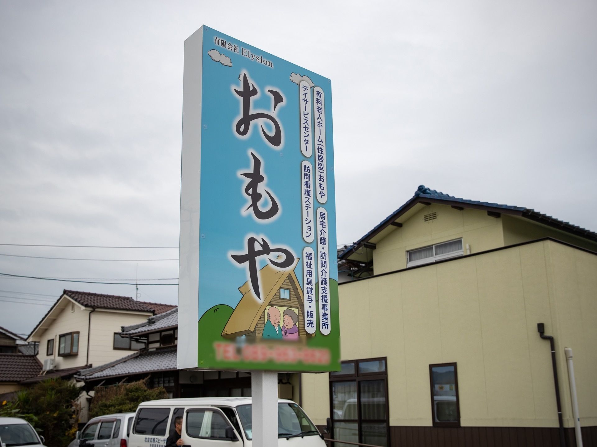 施設の紹介を掲げた看板が立っている。懐かしさと温かさを感じることができるイラストで、日本風の書体で、文字が書かれている。