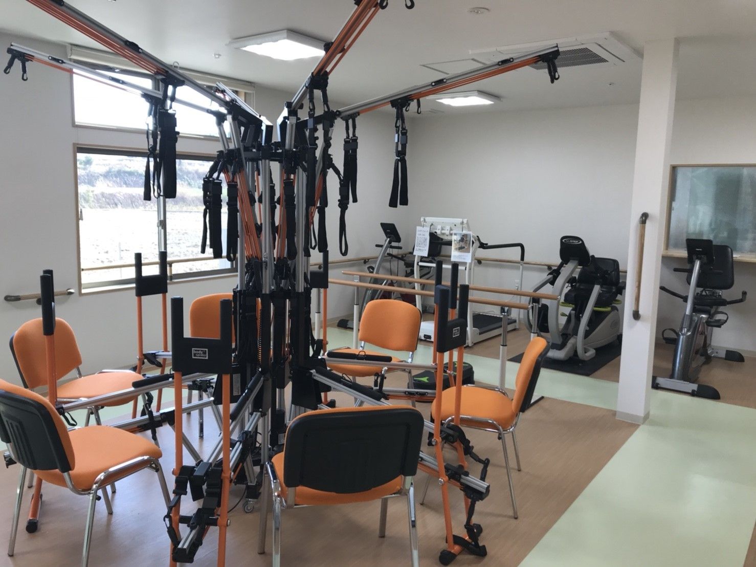 様々な運動器具が並べて置かれた、窓のあるスポーツジム